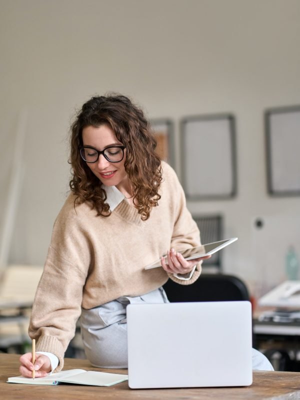 young-smiling-business-woman-working-in-office-using-digital-tablet-vertical